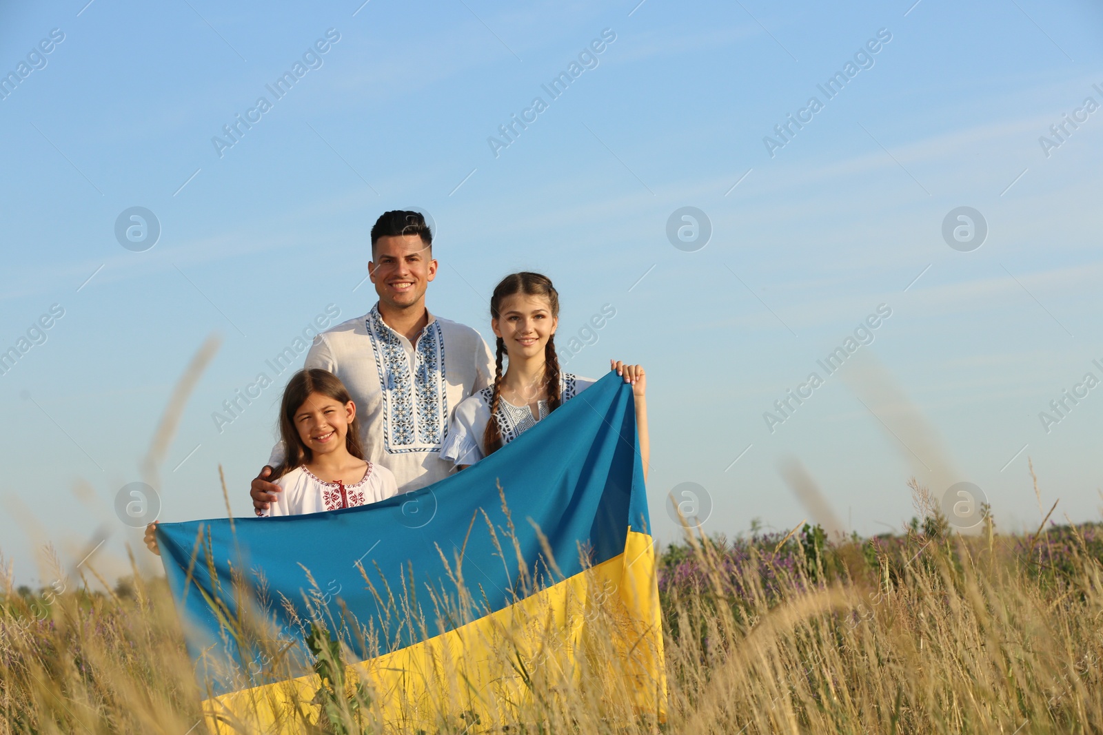 Photo of Family holding national flag of Ukraine in field. Space for text