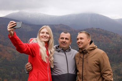 Friends taking selfie together in mountains on autumn day