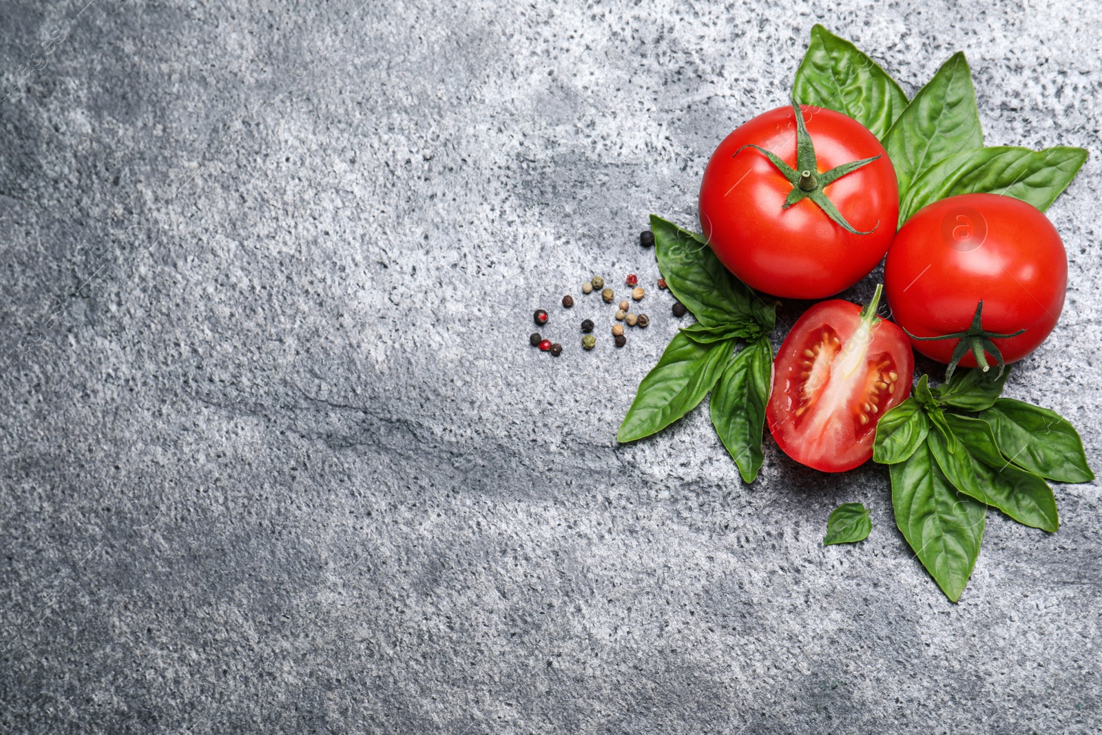 Photo of Flat lay composition with fresh basil leaves and tomatoes on grey table. Space for text