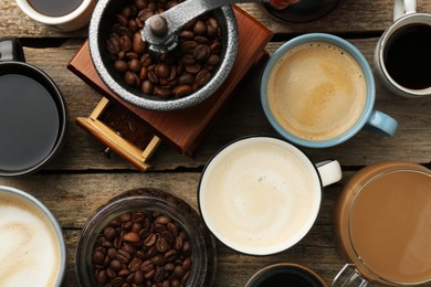 Photo of Different coffee drinks in cups, beans and manual grinder on wooden table, flat lay
