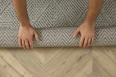 Man rolling out new carpet flooring indoors, top view. Space for text