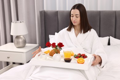 Photo of Young woman having breakfast in bed at home