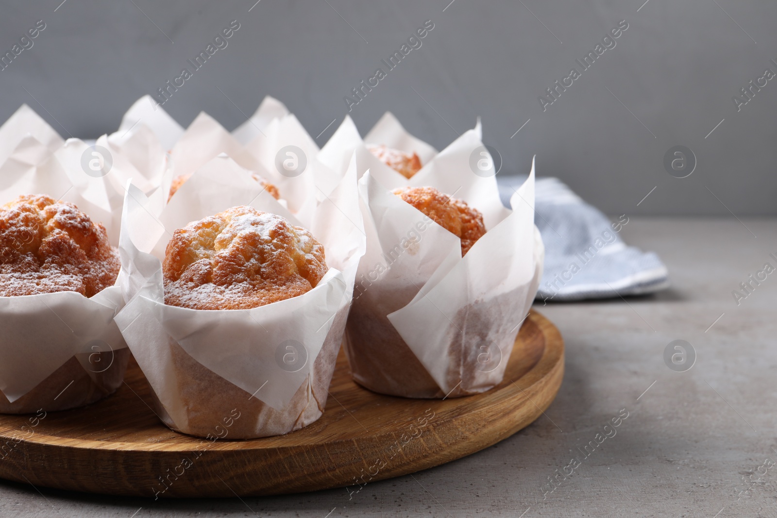 Photo of Delicious muffins with powdered sugar on grey table, closeup