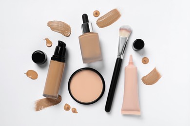 Photo of Liquid foundations, makeup brush, swatches and face powder on white background, flat lay