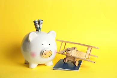 Piggy bank with toy airplane and passport on color background. Travel agency