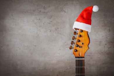 Photo of Guitar with Santa hat on grey background, space for text. Christmas music