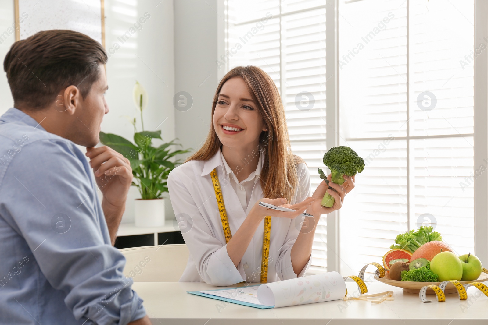 Photo of Young nutritionist consulting patient at table in clinic