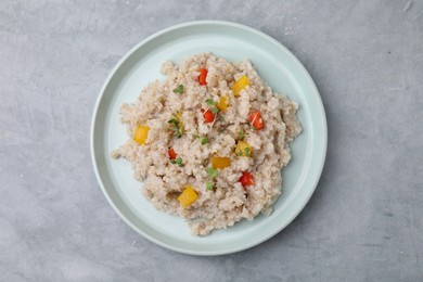 Photo of Delicious barley porridge with vegetables and microgreens on gray table, top view