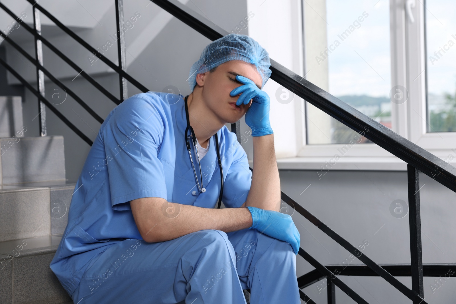 Photo of Exhausted doctor sitting on stairs in hospital