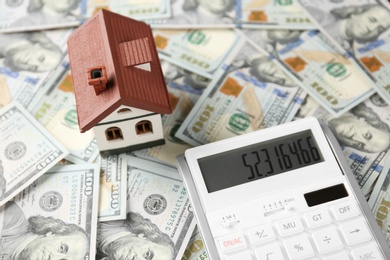 Photo of Calculator and house model on banknotes. Real estate agent concept