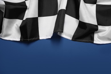 Photo of Checkered finish flag on blue background, top view. Space for text