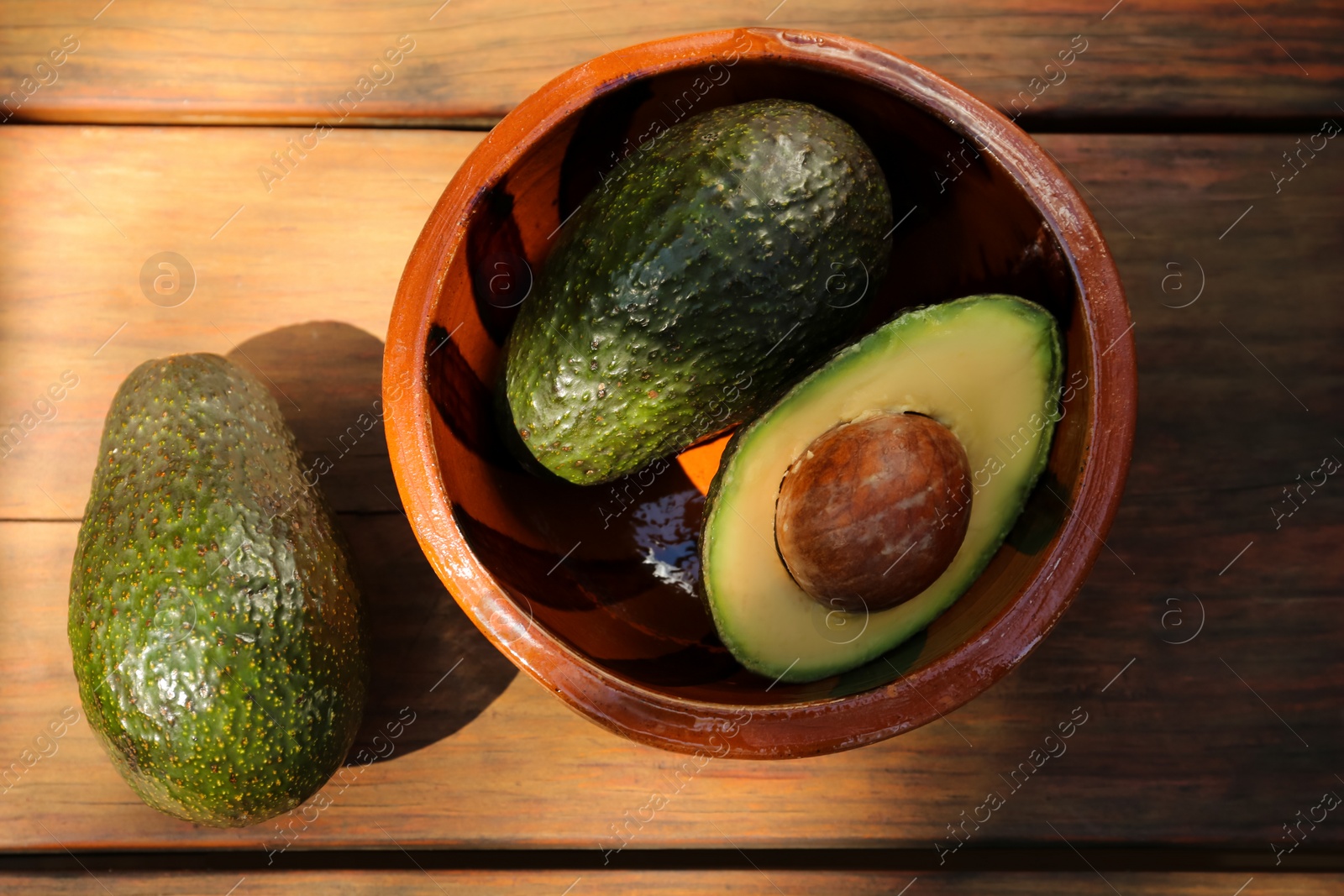 Photo of Tasty fresh avocados on wooden table, flat lay