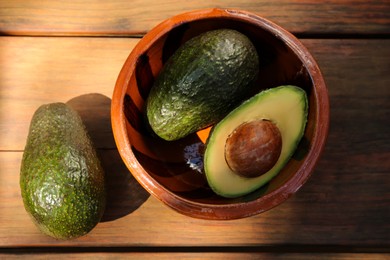 Photo of Tasty fresh avocados on wooden table, flat lay