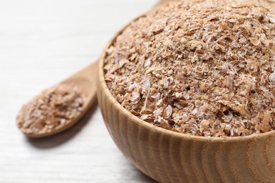 Photo of Bowl of wheat bran on white wooden table, closeup