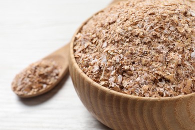 Bowl of wheat bran on white wooden table, closeup