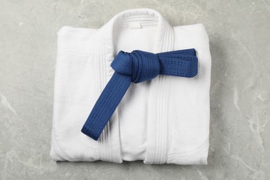 Photo of Blue karate belt and white kimono on gray marble background, top view