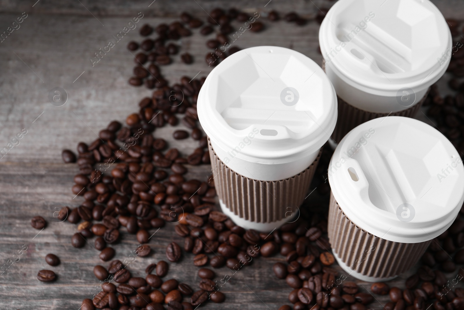 Photo of Coffee to go. Paper cups and roasted beans on wooden table, space for text