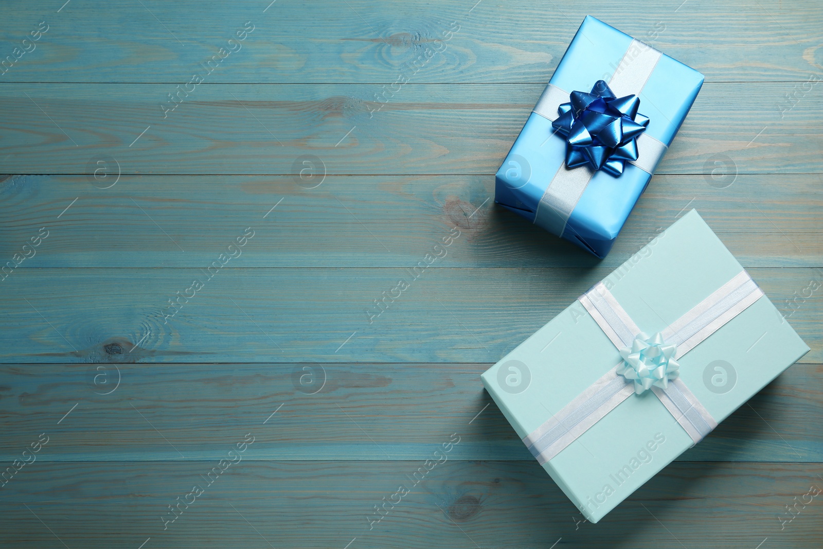 Photo of Gift boxes on light blue wooden table, flat lay. Space for text