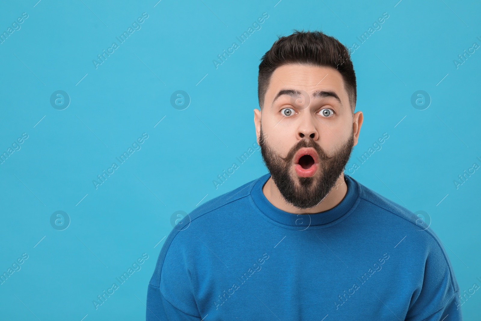 Photo of Surprised young man with mustache on light blue background. Space for text