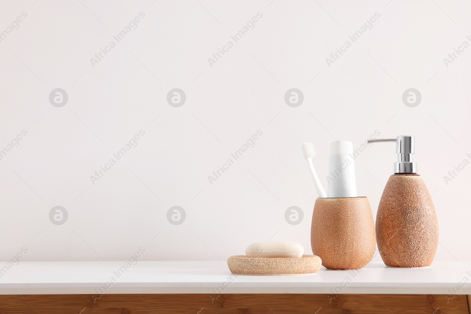 Photo of Different bath accessories and personal care products on table near white wall, space for text