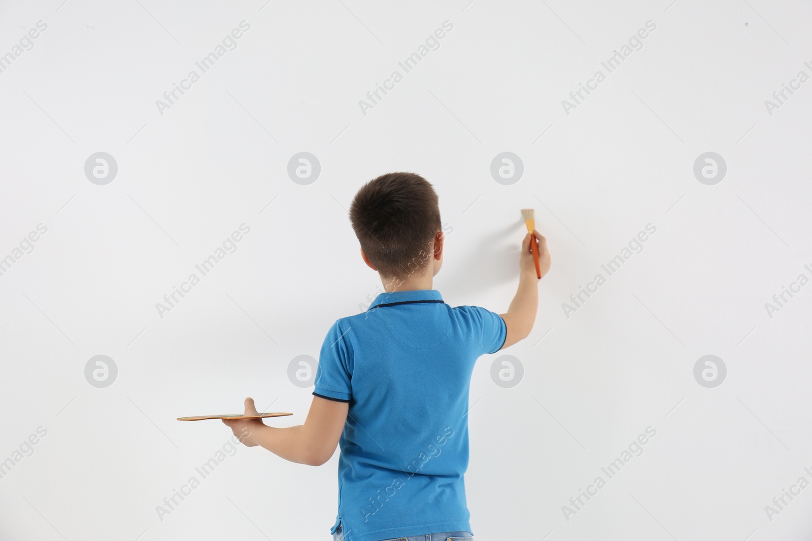 Photo of Little child painting on white wall indoors