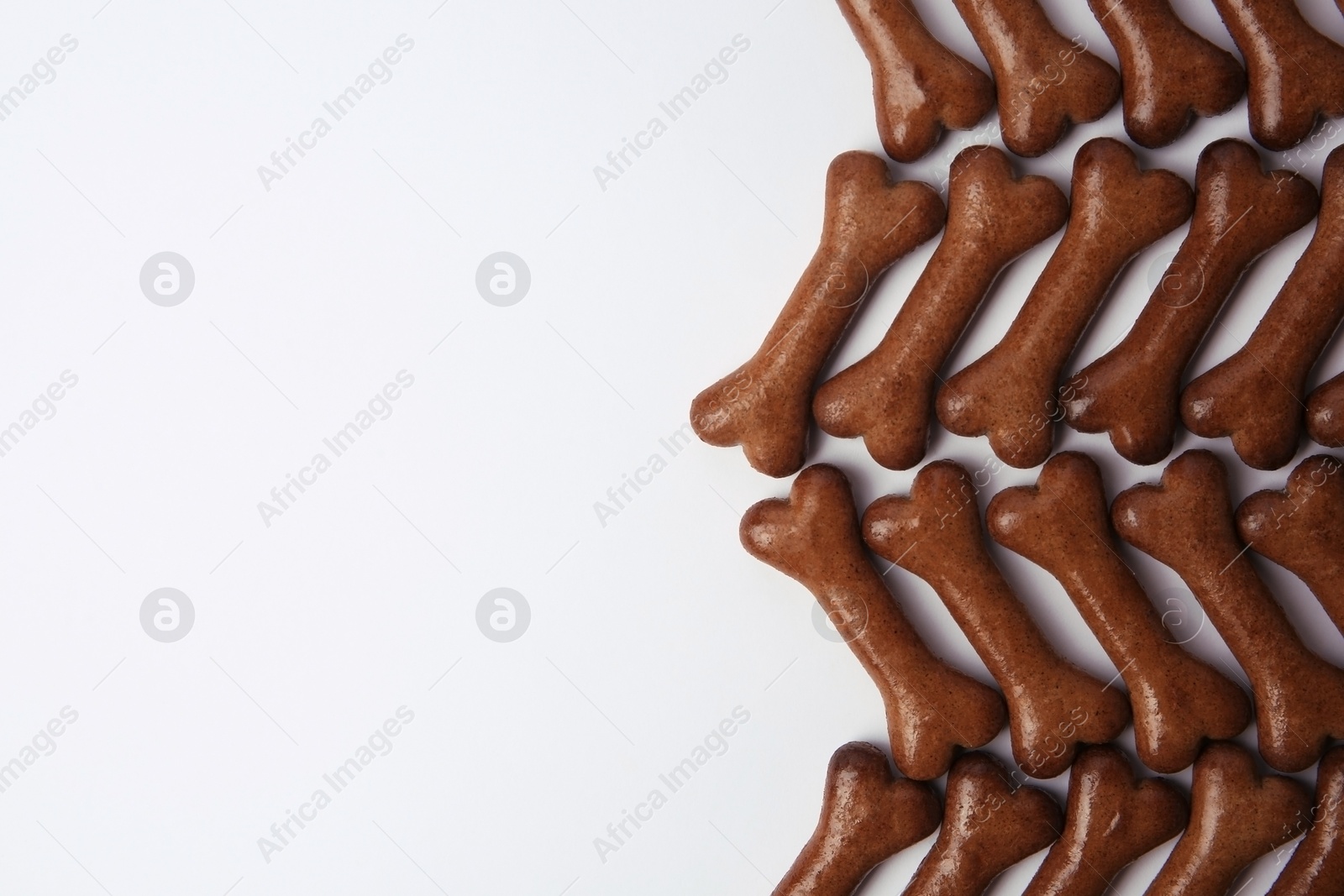 Photo of Bone shaped dog cookies on white background, flat lay. Space for text