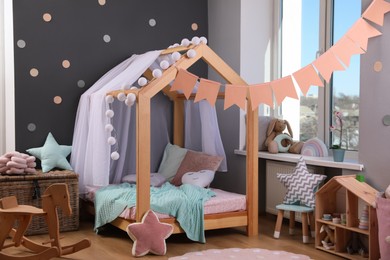 Stylish child room interior with house bed and different toys