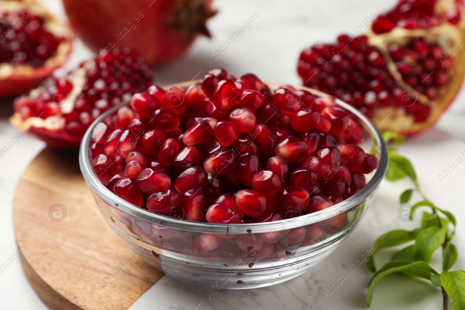 Photo of Ripe juicy pomegranate grains in bowl on white table, closeup