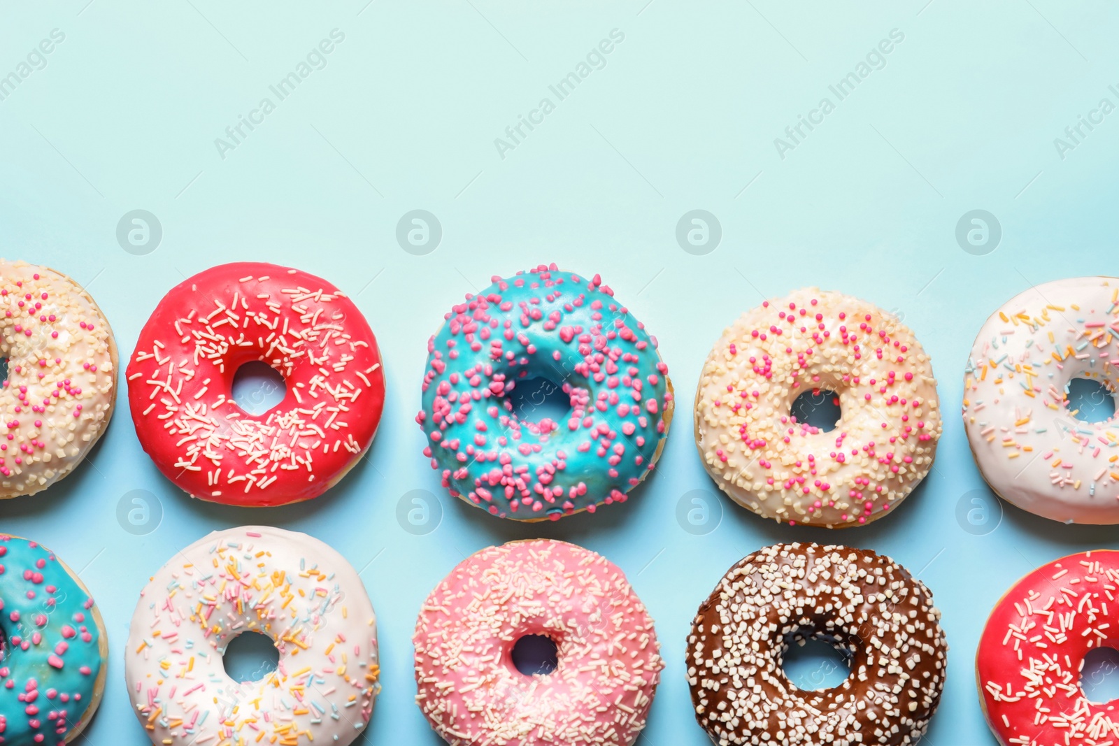 Photo of Delicious glazed doughnuts on color background, top view