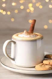 Photo of Cup of delicious eggnog with cinnamon and cookies on wooden table