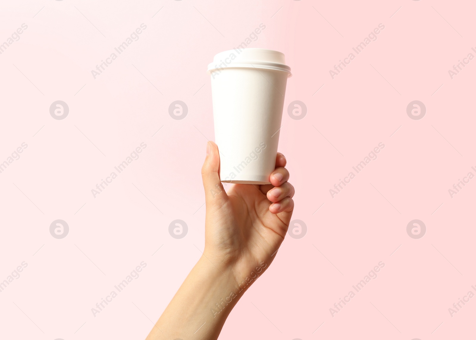 Photo of Woman holding takeaway paper coffee cup on pink background, closeup