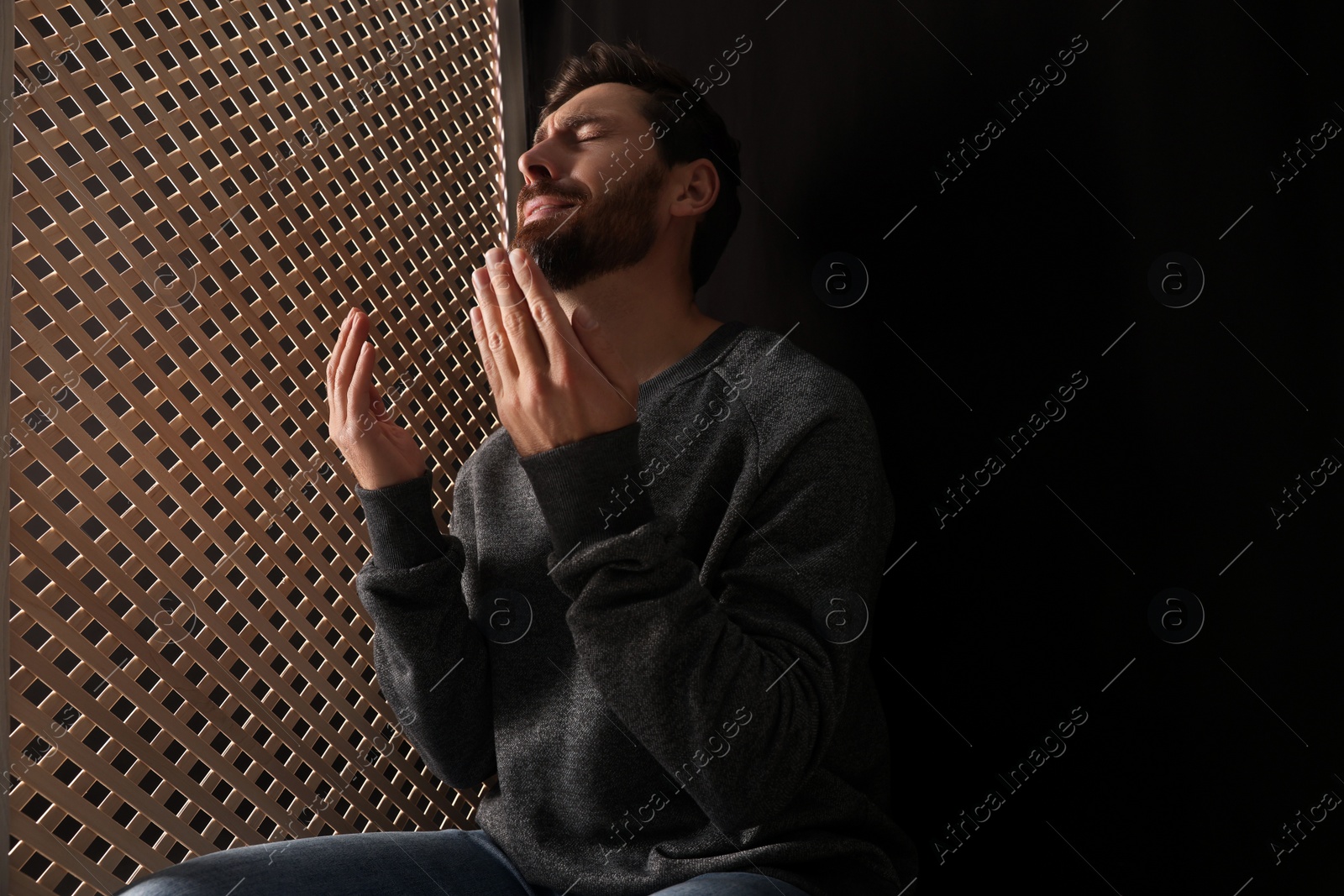 Photo of Upset man praying to God during confession in booth, space for text