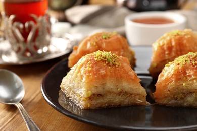 Photo of Delicious sweet baklava with pistachios on wooden table, closeup