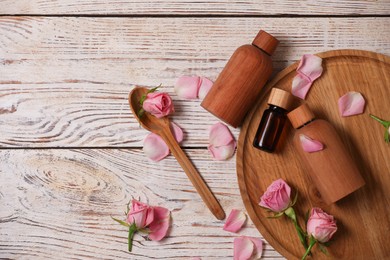 Photo of Flat lay composition with essential rose oil and flowers on white wooden table
