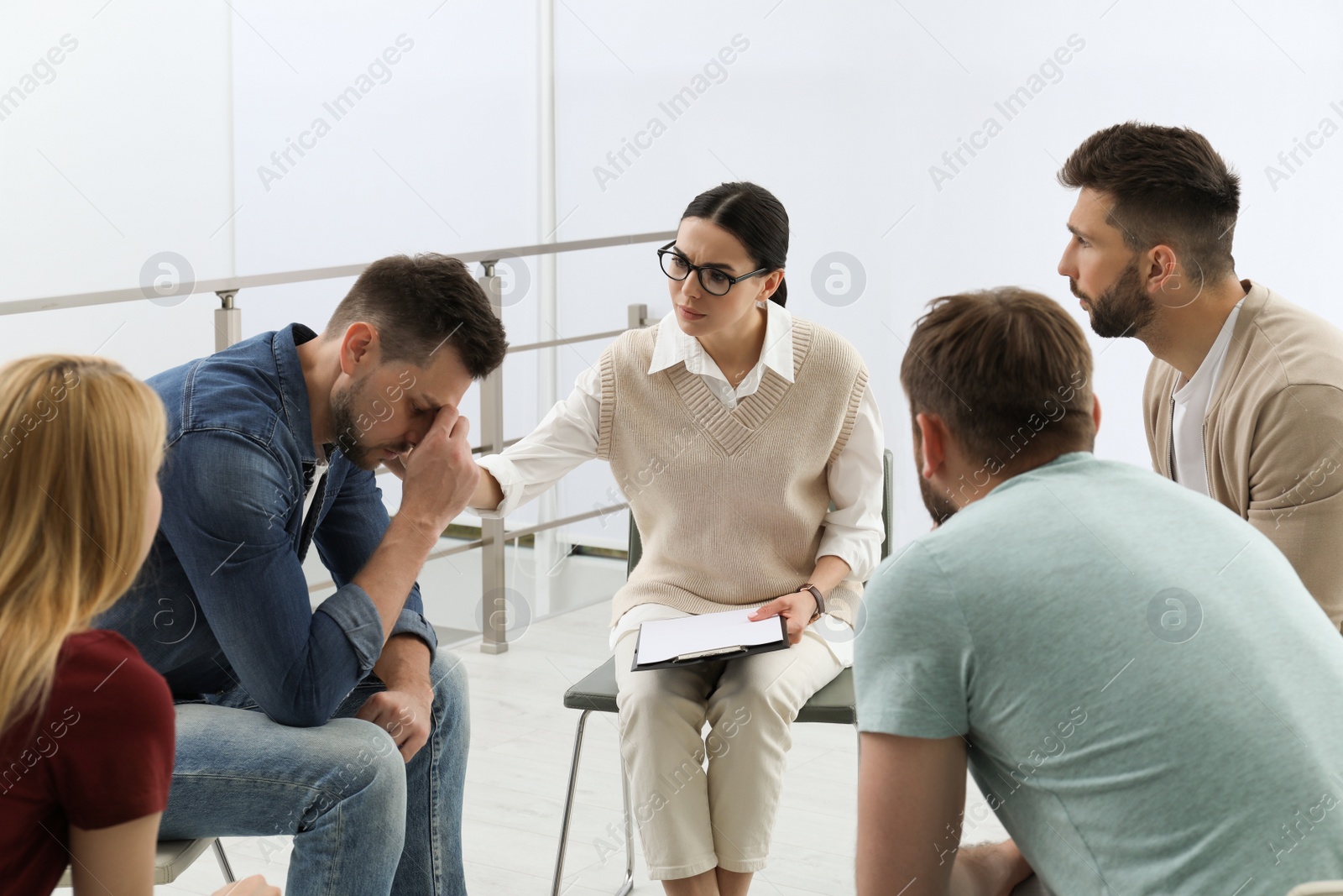 Photo of Psychotherapist working with group of drug addicted people at therapy session indoors