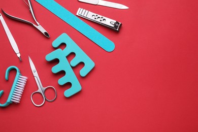 Set of pedicure tools on red background, flat lay. Space for text