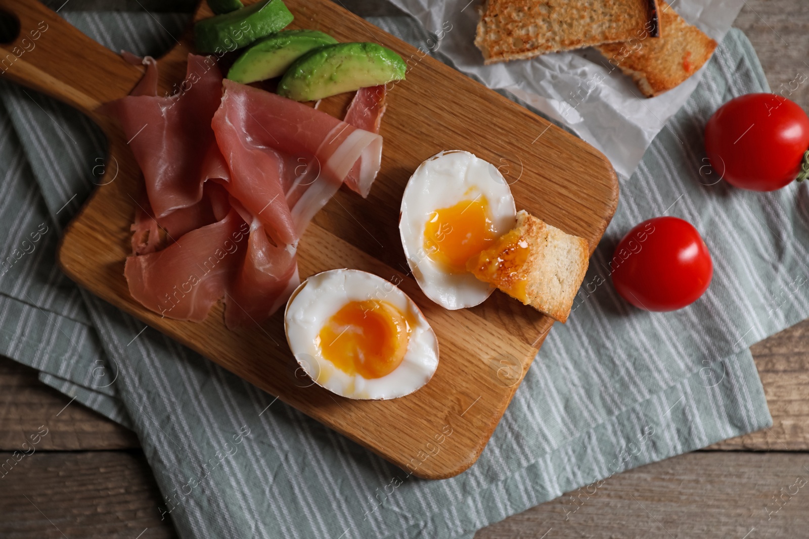 Photo of Delicious breakfast with soft boiled egg and tasty prosciutto served on wooden table, flat lay