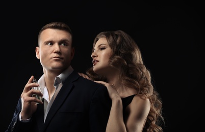 Photo of Passionate woman and handsome man using perfume on black background