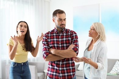 Young man having argument with wife and mother-in-law at home. Family quarrel