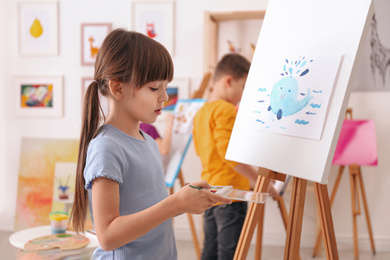 Photo of Cute little child painting during lesson in room