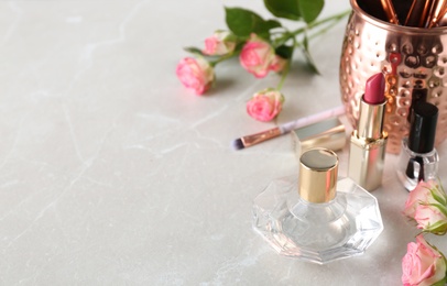 Beautiful composition with lipstick, perfume and nail polish on light table, space for text