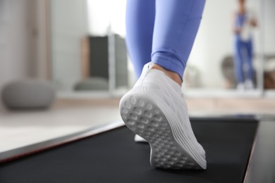 Photo of Sporty woman training on walking treadmill at home, closeup