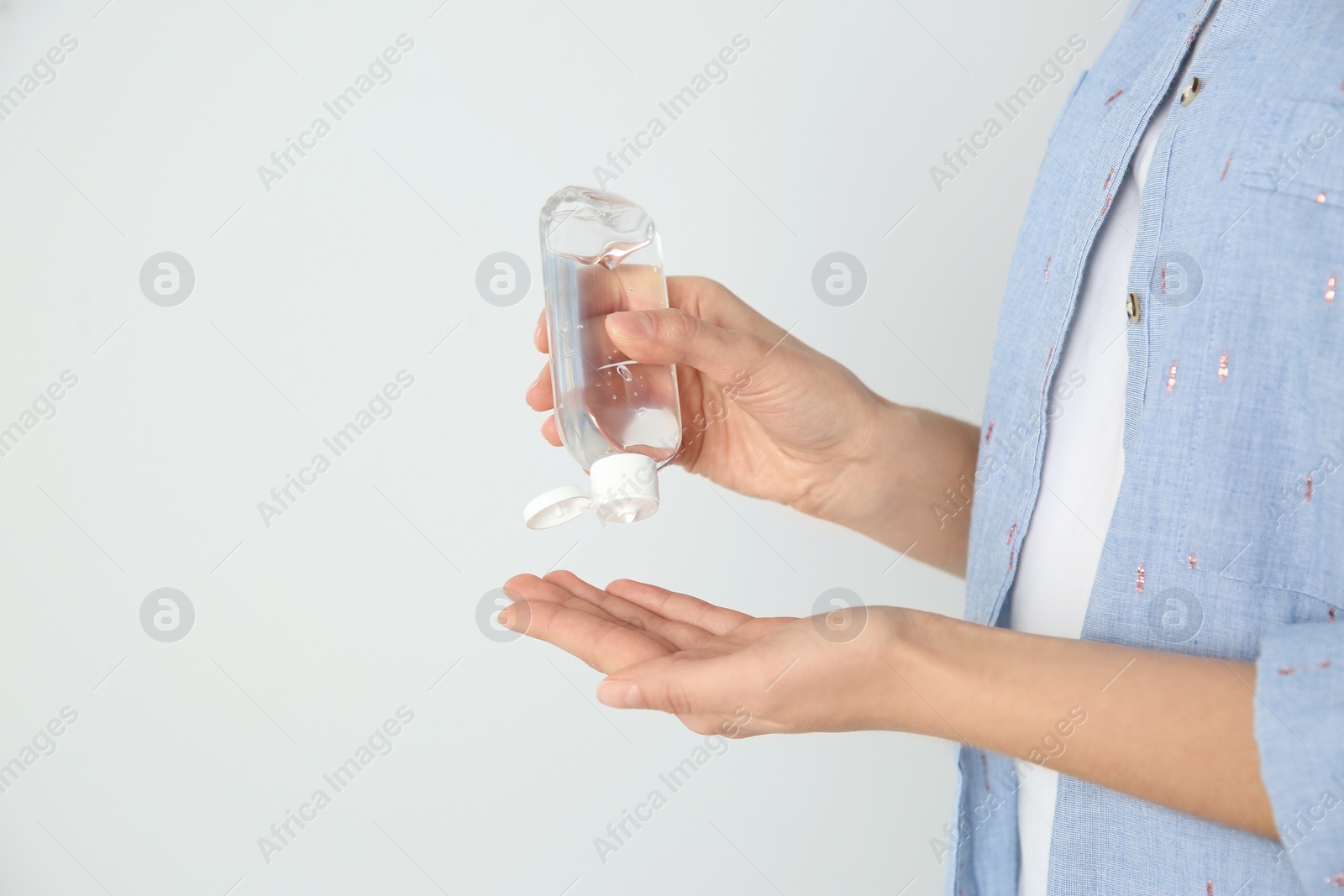 Photo of Woman applying antiseptic gel on light background, closeup