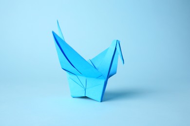 Photo of Origami art. Handmade paper crane on light blue background