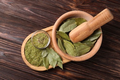 Photo of Whole and ground bay leaves on wooden table, top view