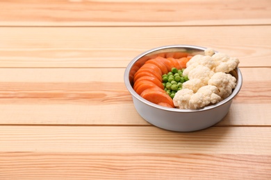 Photo of Bowl with organic dog food on wooden background. Space for text