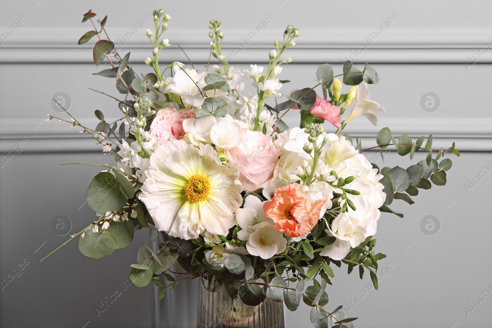 Photo of Bouquet of beautiful flowers near light wall, closeup