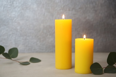 Photo of Candles with floral decor on table against color background