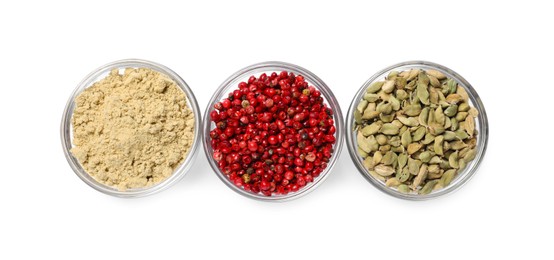 Photo of Bowls with dried cardamom, ginger root powder and red peppercorns on white background, top view