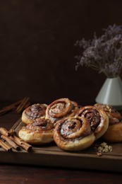 Tasty cinnamon rolls, sticks and nuts on wooden table